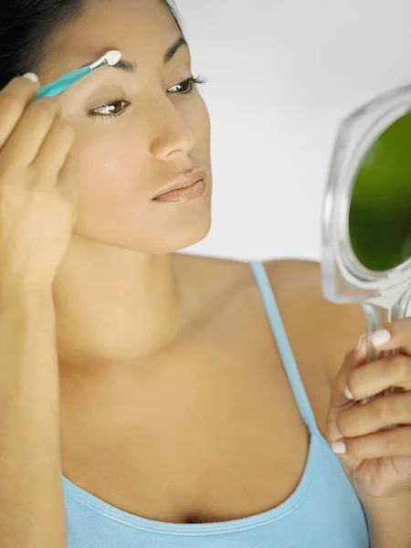 Close-up of a young woman using a make-up brush on her eyebrow