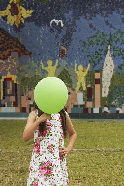 Girl covering her face with a balloon in a park