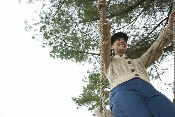 Low angle view of a mature woman swinging on a rope swing