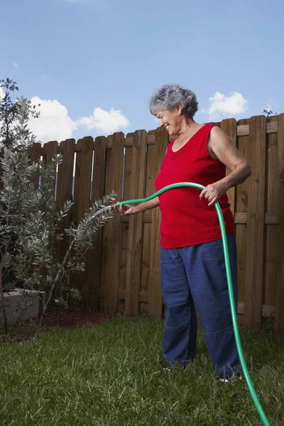 Side profile of a senior woman watering a plant