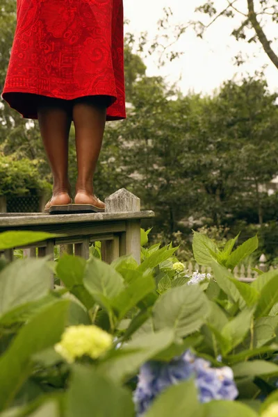 Low section view of a mid adult woman standing on a railing in a park