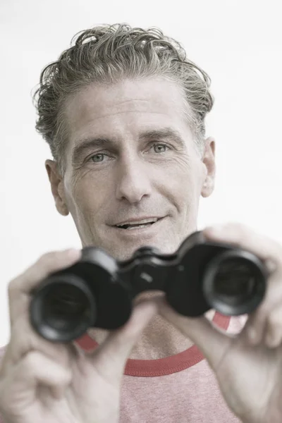Portrait of a mature man holding binoculars and smiling