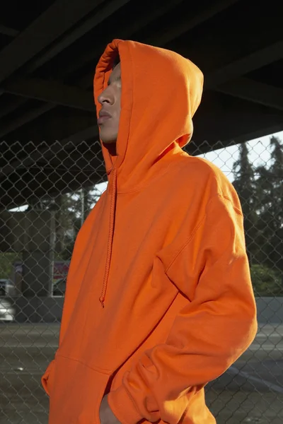 Side profile of a young man wearing a hooded shirt