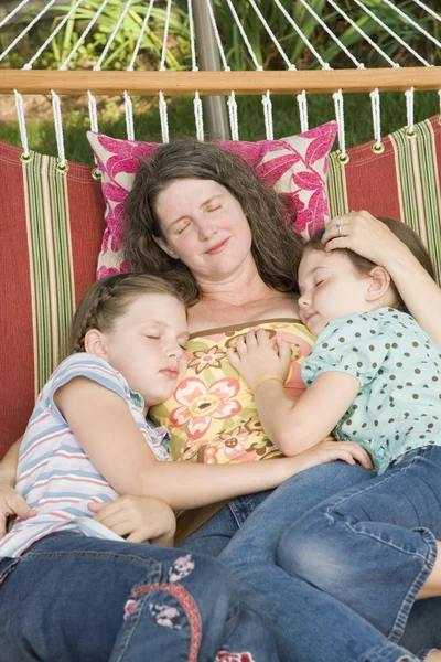 Mature woman sleeping in a hammock with her two daughters