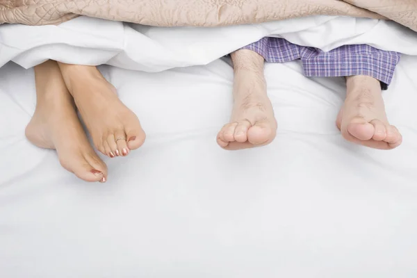 Close-up of a couple\'s feet on the bed