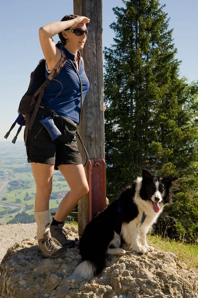 woman with a backpack and a dog on a mountain