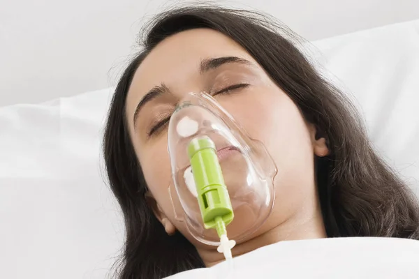 Close-up of a young woman wearing an oxygen mask