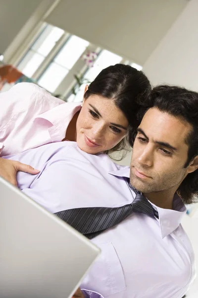 Close-up of a businessman and a businesswoman sitting on the bed using a laptop