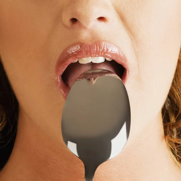 Close-up of a young woman with a spoon in her mouth