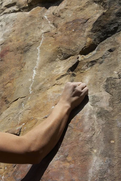 Close-up of a human arm gripping a rock