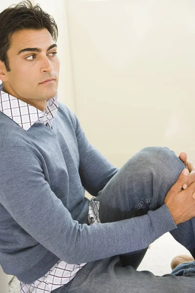 Side profile of a mid adult man sitting on the floor