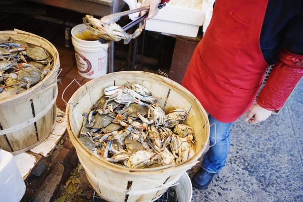 Low section view of a person standing beside a basket full of crabs