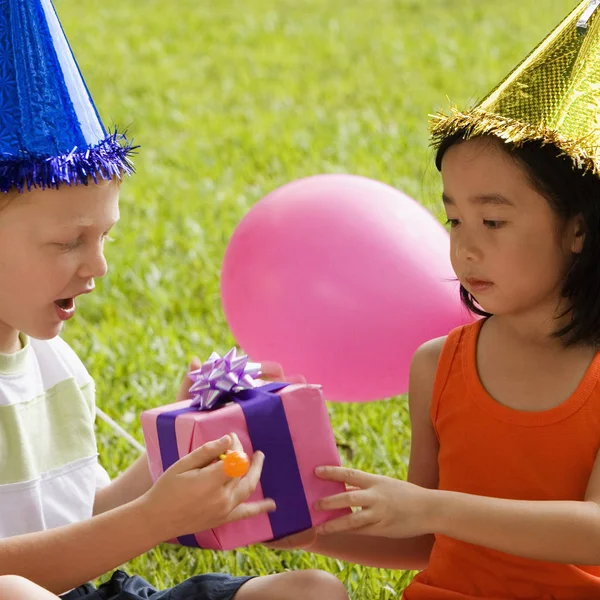 Close-up of a boy giving a birthday present to a girl