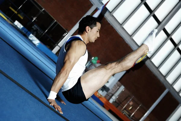 Side profile of a male gymnast balancing on his hands
