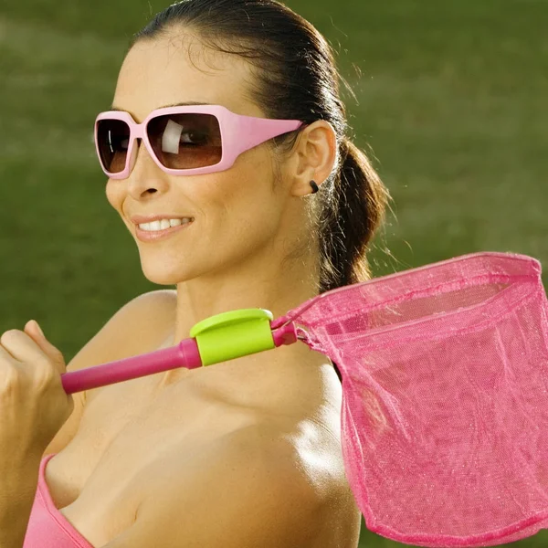 Side profile of a mid adult woman holding a butterfly net