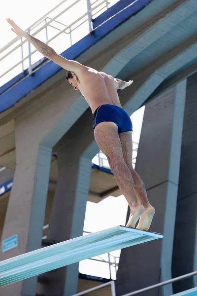 Low angle view of a mid adult man preparing to back dive from a diving board