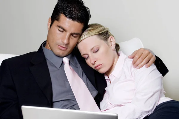 Businessman and a businesswoman sleeping in front of a laptop