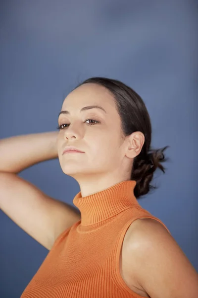 Close-up of a young woman looking away with her hands behind her head