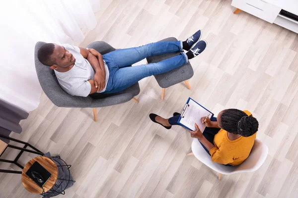 Jonge Afrikaanse Man Zit Stoel Buurt Van Vrouwelijke Psycholoog Met — Stockfoto