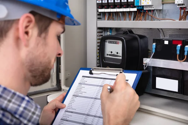 Nahaufnahme Eines Männlichen Technikers Der Auf Klemmbrett Vor Einem Sicherungskasten — Stockfoto