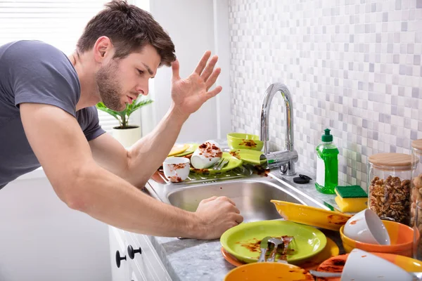 Triste Jovem Olhando Para Sujos Utensílios Perto Dissipador Cozinha — Fotografia de Stock