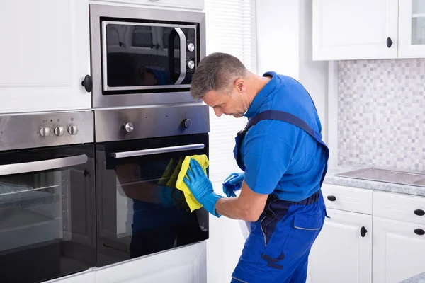 Close Homem Sorridente Faxineiro Forno Limpeza Com Guardanapo Amarelo Cozinha — Fotografia de Stock