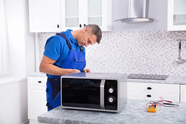 Side View Mature Man Repairing Micmicrowave Oven Kitchen — стоковое фото