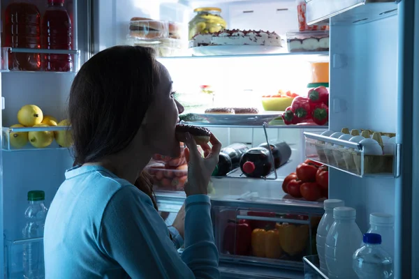 Vista Lateral Una Joven Mujer Parada Frente Refrigerador Comiendo Rosquilla — Foto de Stock