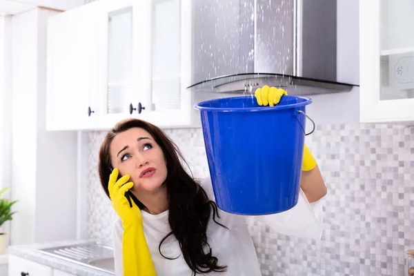 Worried Young Woman Calling Plumber Cellphone Collecting Water Leaking Ceiling — Stock Photo, Image