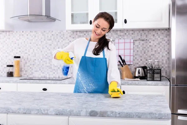 Gülümseyen Kadın Hademe Üniformalı Temizlikçi Mutfak Tezgahını Sprey Şişeyle Temizliyor — Stok fotoğraf