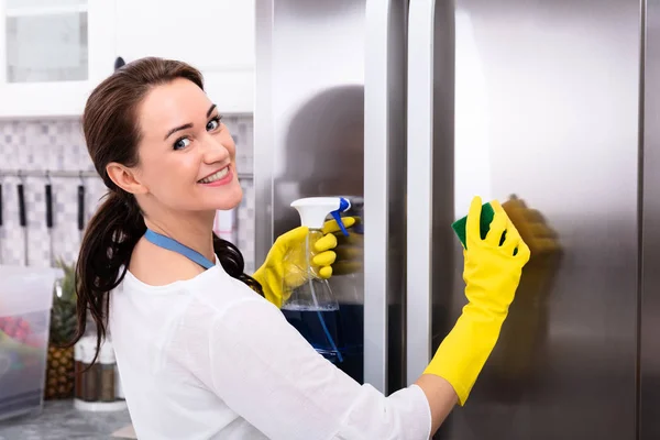 Gelukkig Jonge Vrouw Reiniging Koelkast Met Spons Fles Spray — Stockfoto