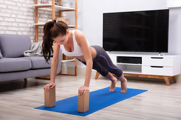 Passer Ung Kvinde Ved Hjælp Træblokke Mens Laver Motion Yogamat - Stock-foto