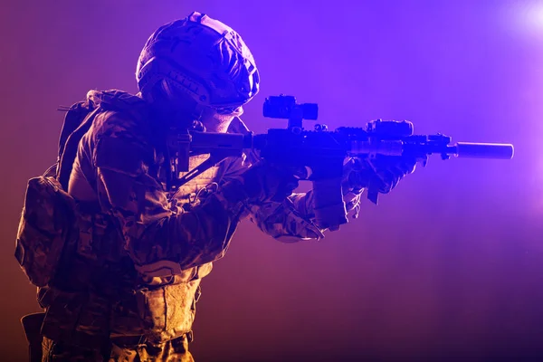 陸軍特殊部隊の現代兵士 戦闘制服の警察対テロ部隊戦闘機 短砲身アサルトライフルを目的としたナイトビジョン装置付きヘルメット 赤バックライト付き低キースタジオ撮影 — ストック写真