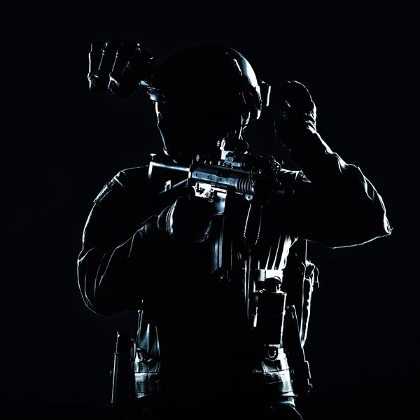 特殊作戦兵士 マスクと眼鏡のSwatチーム戦闘機 装備されたナイトビジョン装置 武装した短砲身サービスライフル 振り返ってフリーズハンド信号を示す 低キースタジオ撮影 — ストック写真