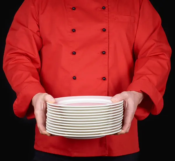 Cocinero Uniforme Rojo Sostiene Sus Manos Una Pila Platos Blancos —  Fotos de Stock