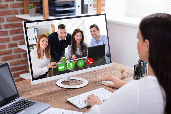 一个年轻女商人与她的同事在电脑上举行视频会议的侧视图 — 图库照片