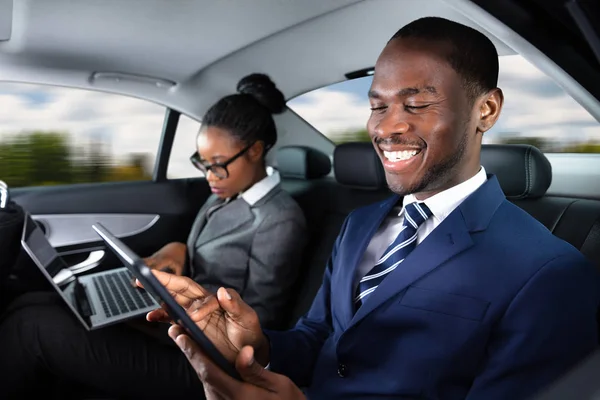 Two Happy African Businesspeople Using Electronic Devices While Traveling Car — Stock Photo, Image