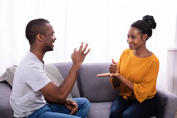 Smiling Young Couple Sitting Sofa Communicating Sign Languages — Stok Foto