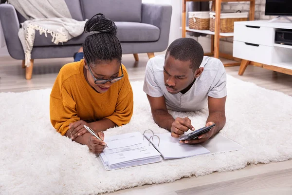 Jonge Afrikaanse Paar Liggend Tapijt Factuur Met Calculator — Stockfoto