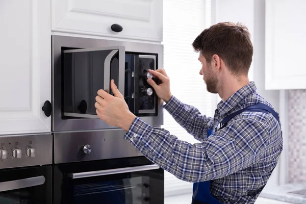 Vista Lateral Jovem Homem Reparando Forno Microondas Cozinha — Fotografia de Stock