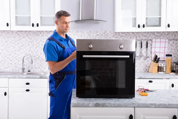 成熟的男性技师修理厨房工作台上的烤箱 — 图库照片