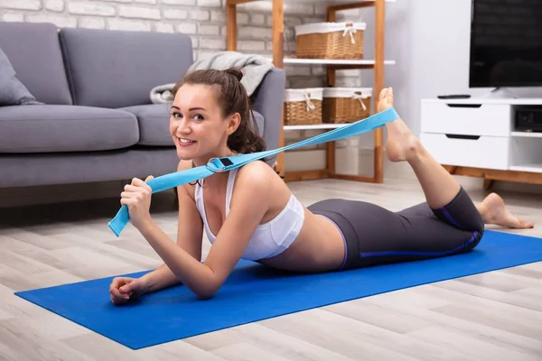 Glad Ung Kvinde Sportstøj Gør Træning Med Yoga Bælte Hjemme - Stock-foto