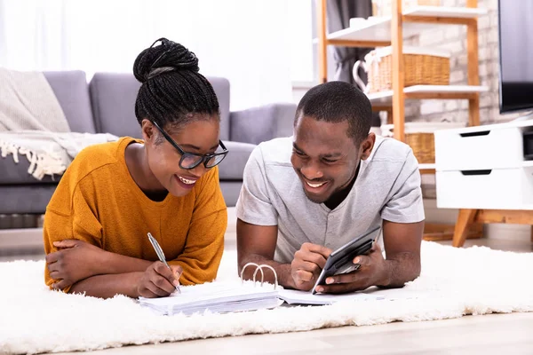 Unga Afrikanska Par Liggande Matta Faktura Med Miniräknare — Stockfoto