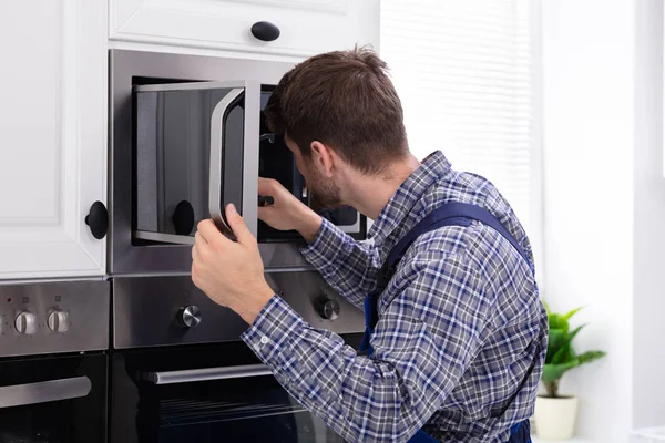 Vista Lateral Jovem Homem Reparando Forno Microondas Cozinha — Fotografia de Stock