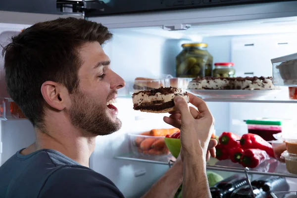 Portré Egy Boldog Ember Eszik Torta Közelében Nyitott Hűtő — Stock Fotó