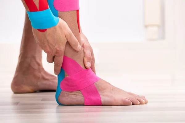 Sert Ahşap Zeminde Duran Fiziksel Bantlı Erkek Ayağının Yakın Çekimi — Stok fotoğraf