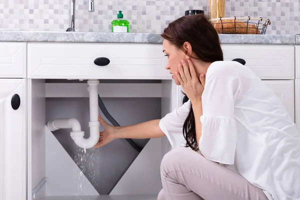 Bakifrån Kvinna Som Försöker Stoppa Vattenläckage Från Sink Pipe Köket — Stockfoto