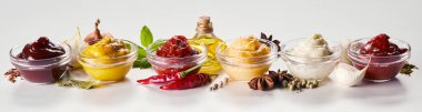 Row of glass bowls with sauces, dressings and marinades with ingredients including aromatic spices, herbs and vegetables on white in a panorama banner clipart
