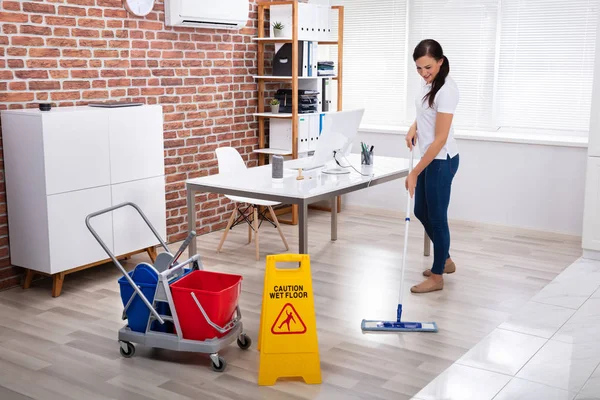 Happy Young Female Janitor Cleaning Floor Office — стоковое фото
