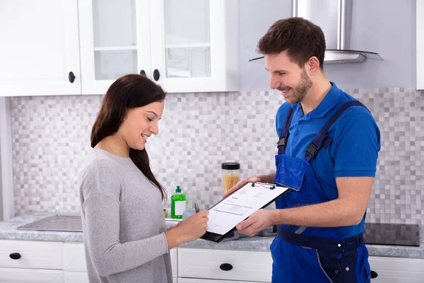 Happy Young Male Plumber Looking Woman Signing Invoice Kitchen Dalam — Stok Foto